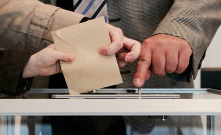 Hands dropping an envelope into a clear box