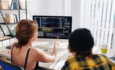 Two individuals review a computer showing the data behind their small business.