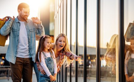 Two adults and a young girl looking at their reflection in a window