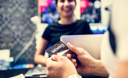 Closeup of hands handing a loyalty credit card to a cashier