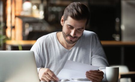 A man sitting at a table and looking at a piece of paper
