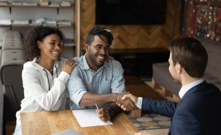 Couple shaking hands with a man seated across the table